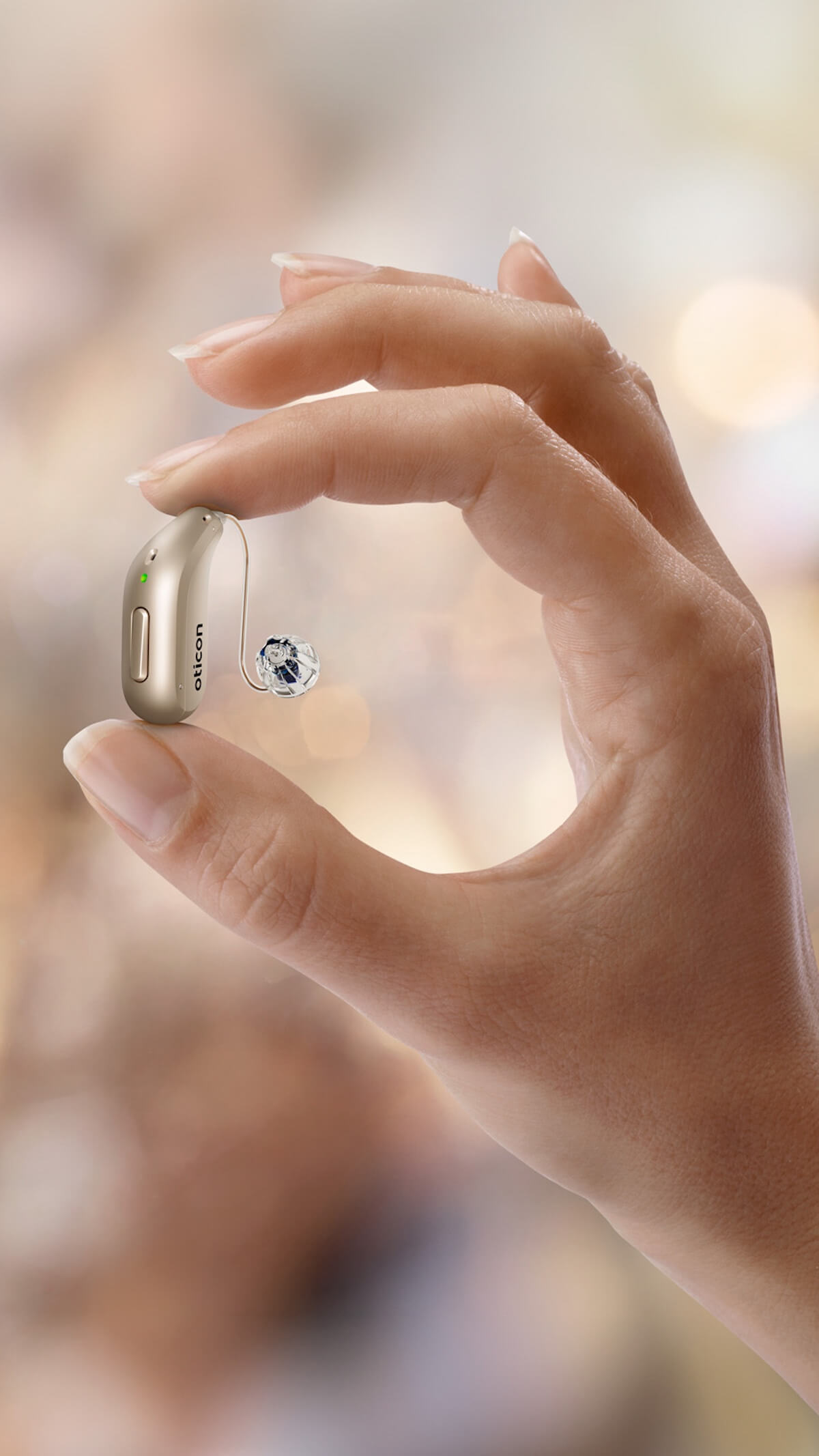 Oticon Reveal hearing aid held in the palm of a hand