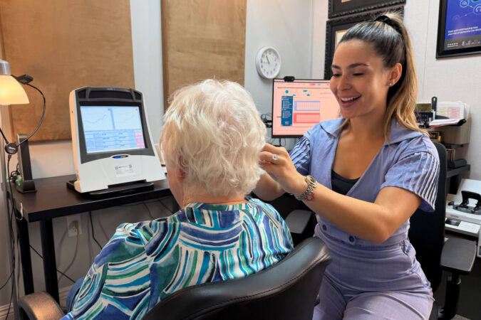 Amazing Hearing audiologist gently examining a patient's ear during a hearing evaluation in Orange County